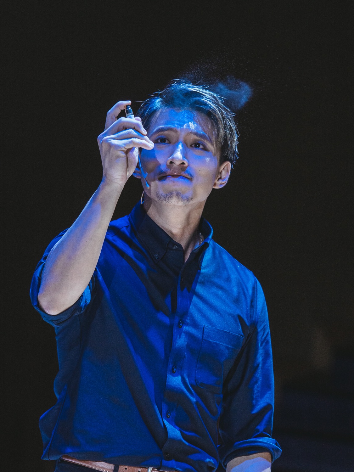 Terrence Leung performing under blue stage light